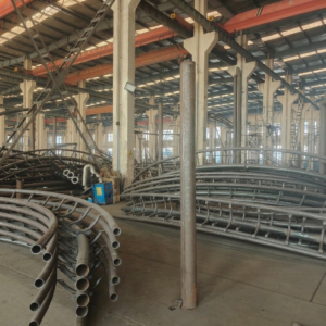 Stacked heavy-duty steel tracks and support poles for amusement rides in manufacturing workshop